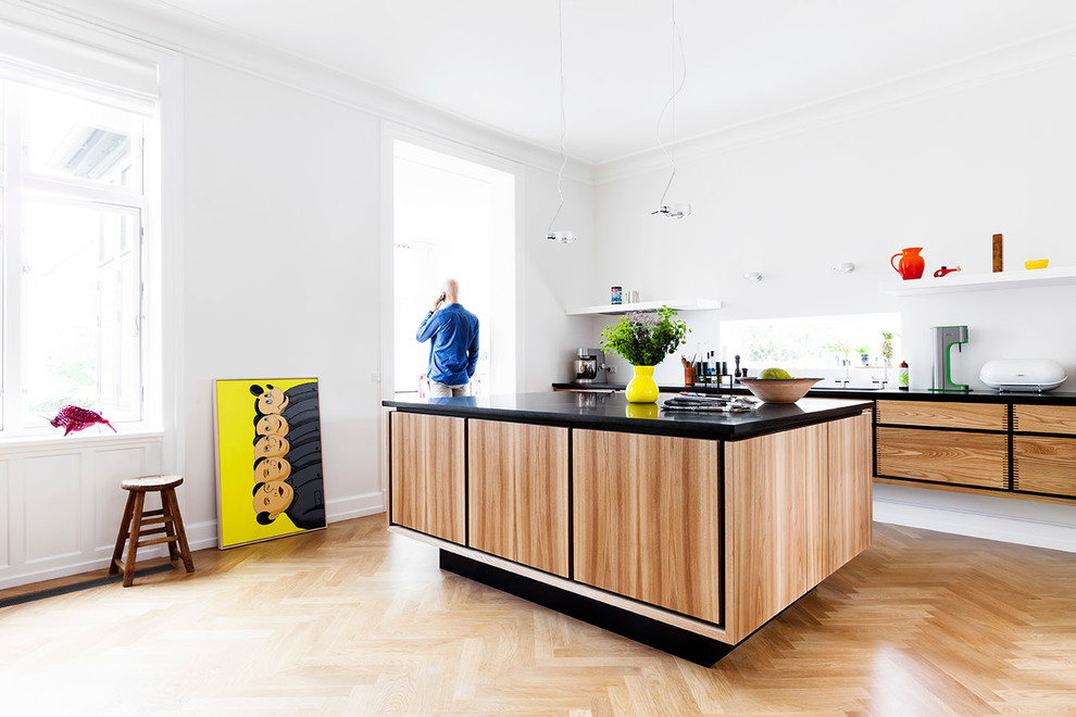 Photo of a large scandinavian single-wall open plan kitchen in Copenhagen with light hardwood floors, with island, flat-panel cabinets, light wood cabinets and granite benchtops.