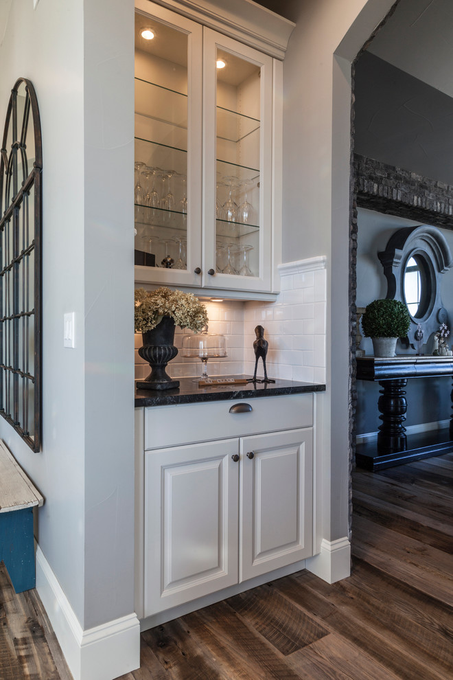 Inspiration for a transitional medium tone wood floor hallway remodel in Denver with a farmhouse sink, raised-panel cabinets, white cabinets, soapstone countertops, white backsplash, subway tile backsplash, stainless steel appliances and an island