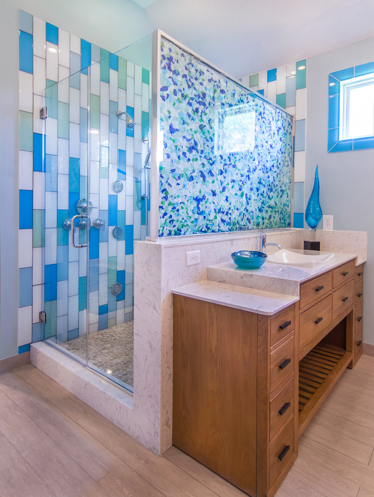 Large beach style master bathroom in Houston with a vessel sink, flat-panel cabinets, light wood cabinets, limestone benchtops, a corner shower, a two-piece toilet, beige tile, glass tile, green walls and light hardwood floors.
