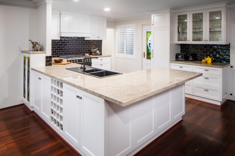 Traditional kitchen in Perth with a drop-in sink, shaker cabinets, white cabinets, granite benchtops, black splashback, subway tile splashback, black appliances, dark hardwood floors and brown benchtop.