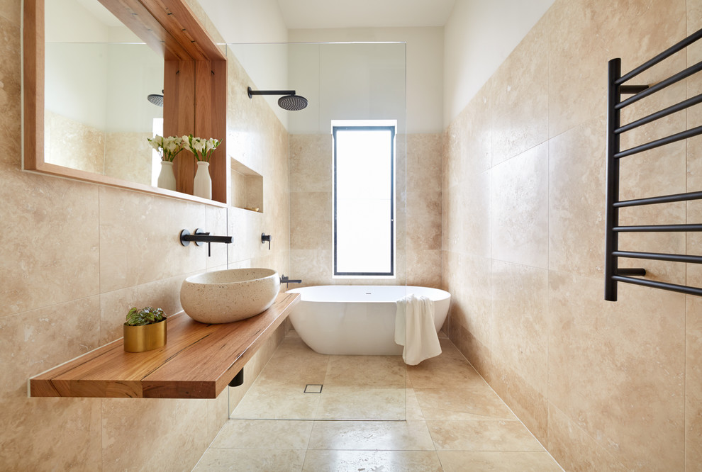 This is an example of a small contemporary 3/4 bathroom in Melbourne with an open shower, brown cabinets, a freestanding tub, an open shower, beige tile, a vessel sink, wood benchtops and brown benchtops.