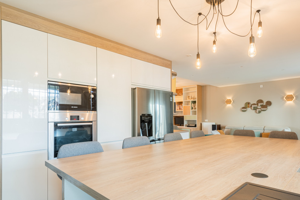 Medium sized contemporary l-shaped kitchen/diner in Paris with flat-panel cabinets, white cabinets, an island, beige worktops, a submerged sink, wood worktops, beige splashback, wood splashback, stainless steel appliances, slate flooring and grey floors.