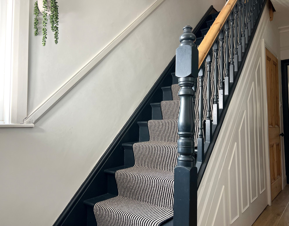 This is an example of a mid-sized traditional carpeted straight staircase with carpet risers and wood railing.