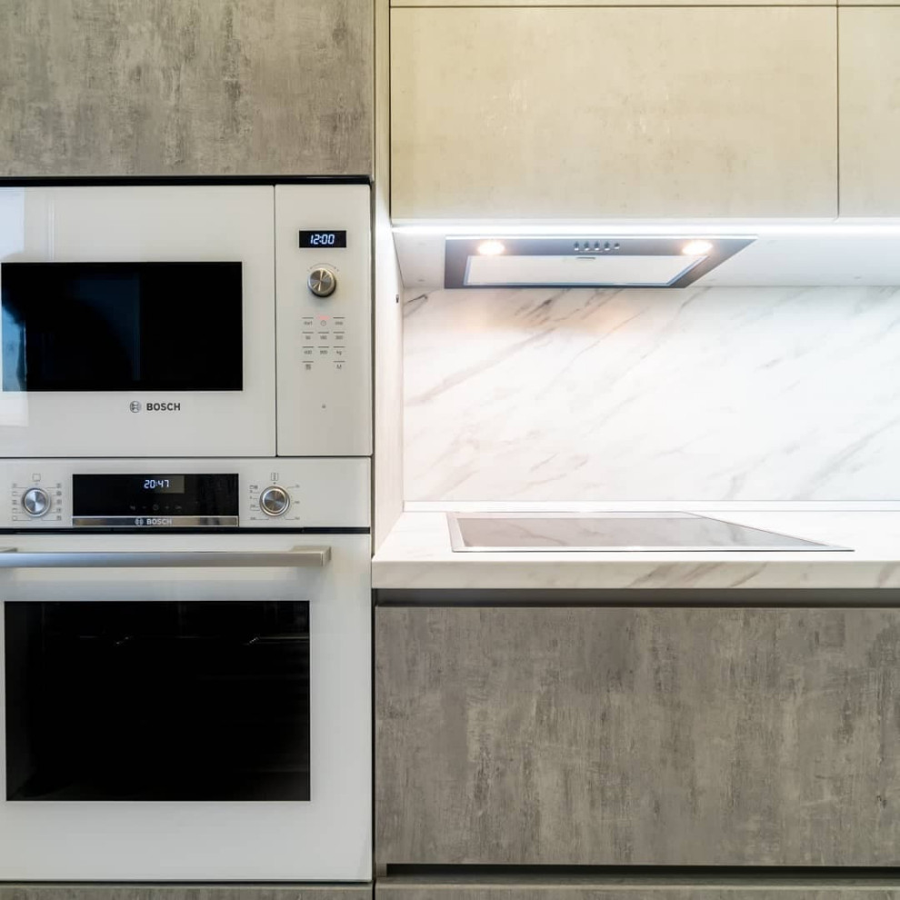 Example of a mid-sized urban l-shaped porcelain tile and white floor eat-in kitchen design in Moscow with a drop-in sink, recessed-panel cabinets, stainless steel cabinets, solid surface countertops, white backsplash, granite backsplash, stainless steel appliances, no island and white countertops