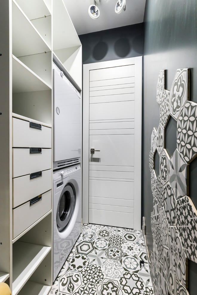 This is an example of a contemporary dedicated laundry room in Moscow with black walls and a stacked washer and dryer.
