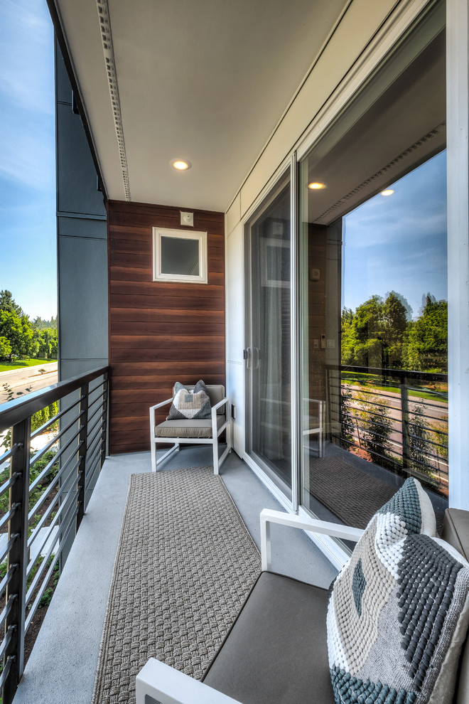 This is an example of a small contemporary balcony in Seattle with a roof extension and metal railing.