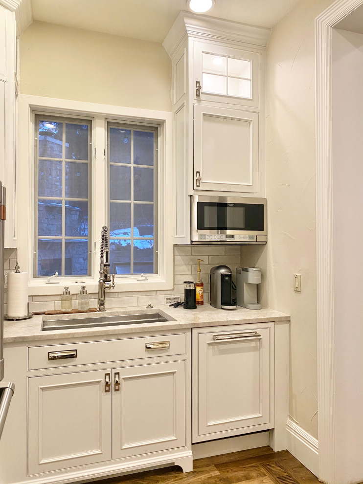 Immagine di una grande cucina chic con lavello sottopiano, ante a filo, ante bianche, paraspruzzi bianco, pavimento marrone e top bianco