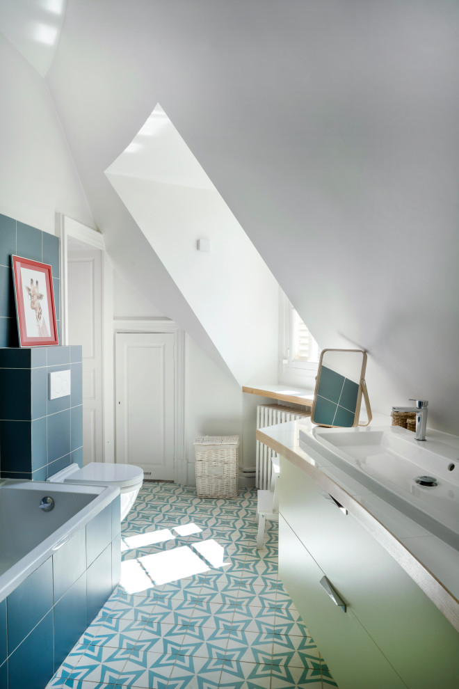 Idéer för funkis blått badrum, med ett undermonterat badkar, en vägghängd toalettstol, blå kakel, keramikplattor, vita väggar, klinkergolv i keramik, ett konsol handfat och blått golv