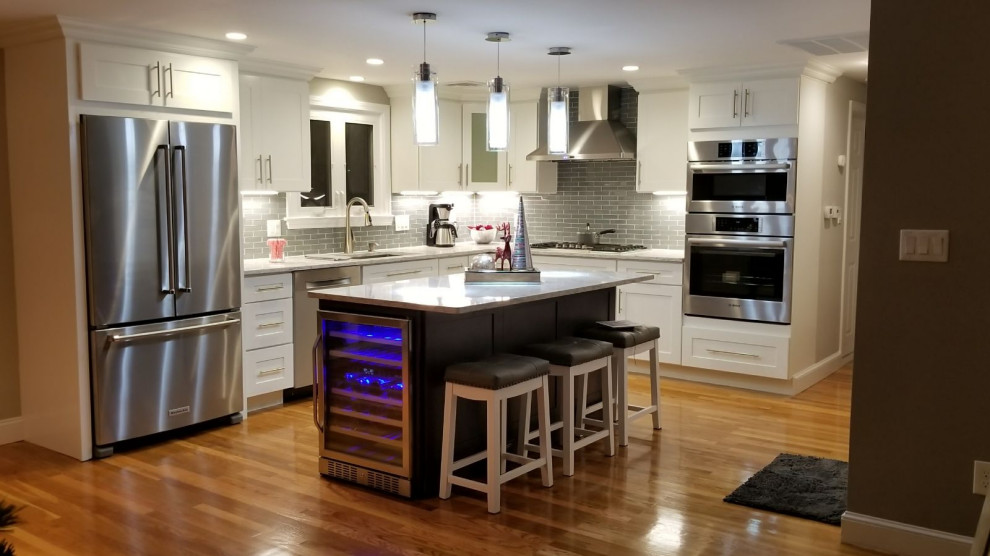 Inspiration for a mid-sized transitional l-shaped dark wood floor and brown floor open concept kitchen remodel with shaker cabinets, white cabinets, gray backsplash, stainless steel appliances, an island, an undermount sink and white countertops