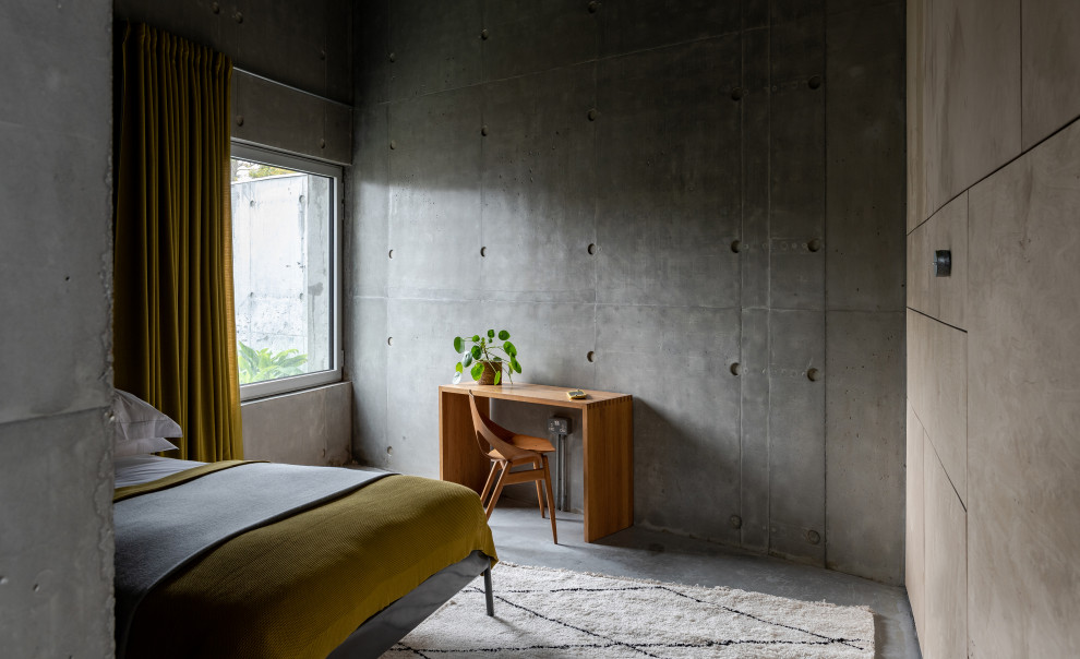 Photo of a medium sized industrial guest and grey and yellow bedroom in Sussex with concrete flooring.