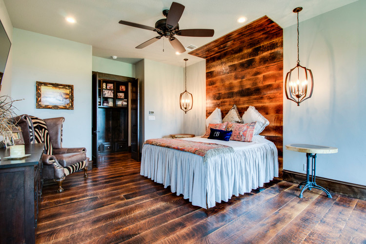 Photo of a country bedroom in Dallas with white walls, no fireplace and brown floor.