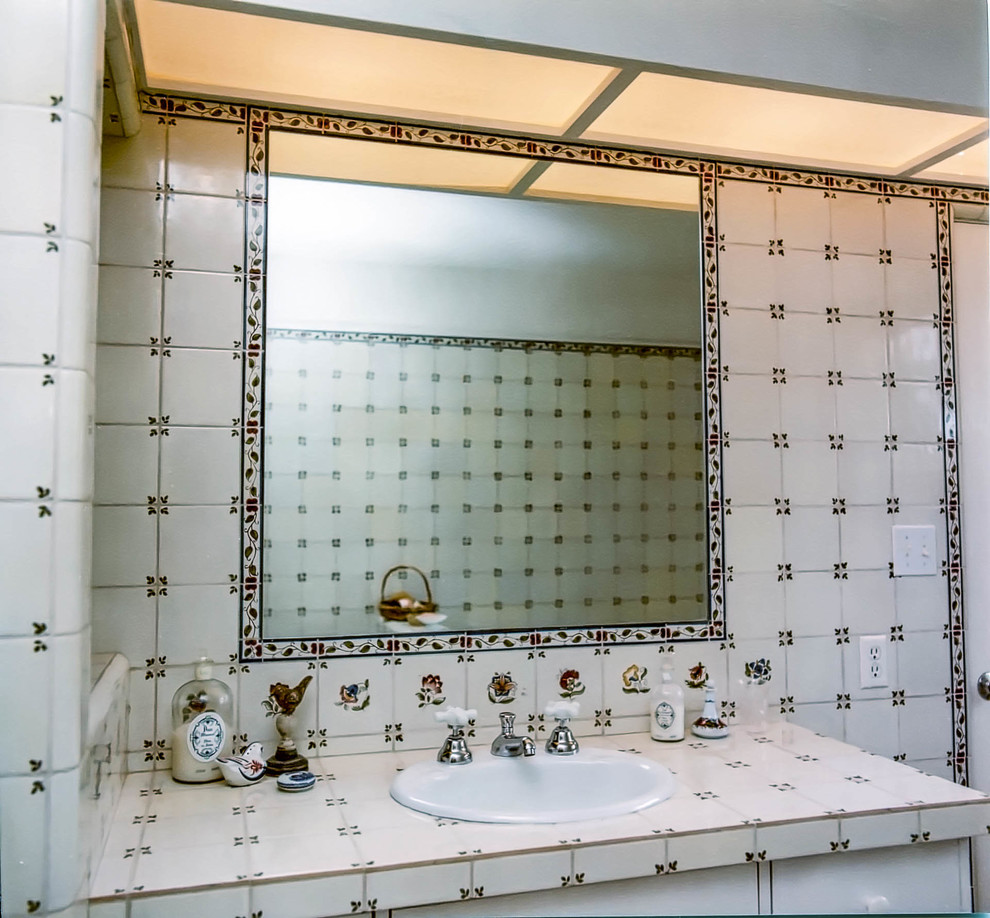 This is an example of a mid-sized eclectic 3/4 bathroom in San Diego with flat-panel cabinets, white cabinets, an alcove tub, a one-piece toilet, white tile, ceramic tile, white walls, ceramic floors, a drop-in sink and tile benchtops.