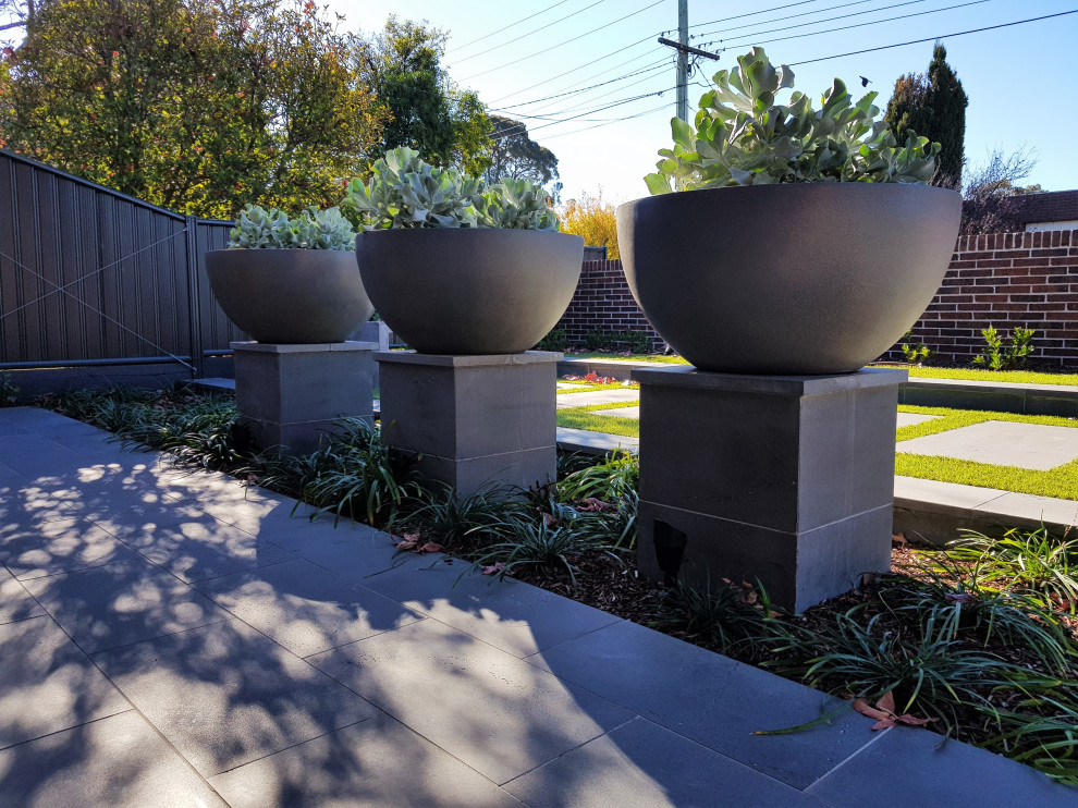 Design ideas for a mid-sized modern front yard partial sun formal garden for summer in Melbourne with with flowerbed and natural stone pavers.