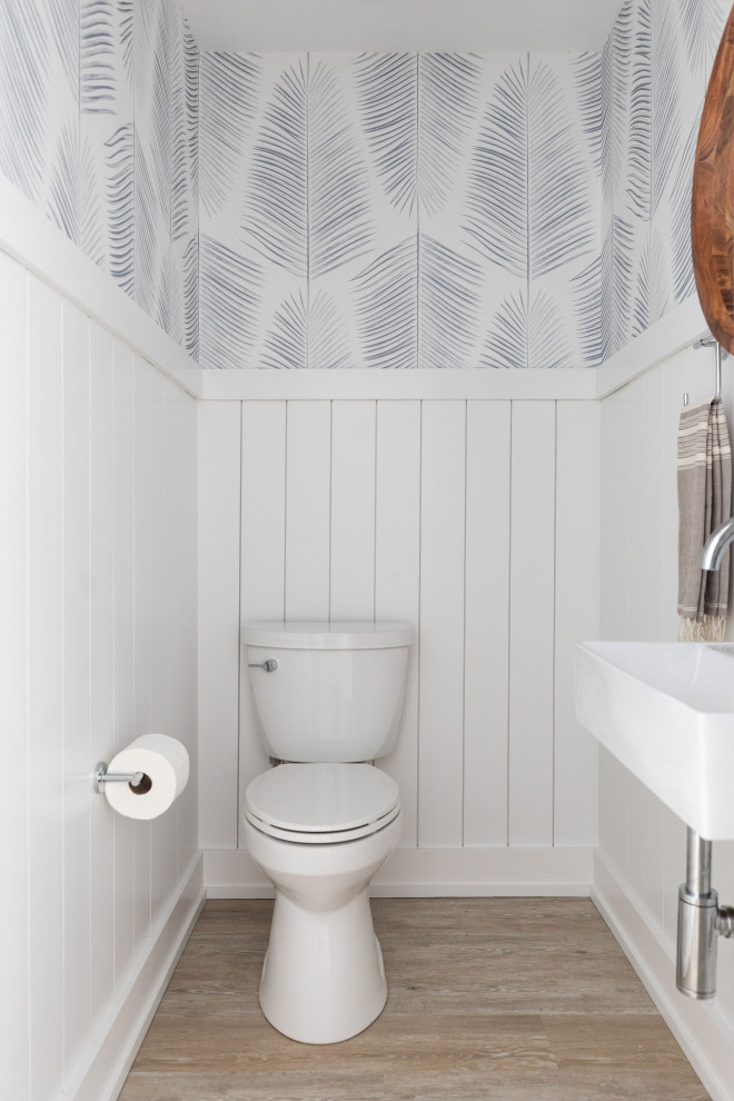 Small beach style powder room in San Diego with a two-piece toilet, white walls, vinyl floors, a wall-mount sink, beige floor, a floating vanity and planked wall panelling.