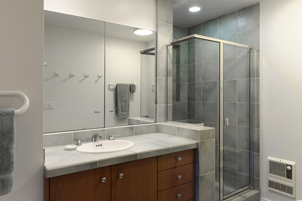 This is an example of a midcentury bathroom in San Diego with flat-panel cabinets, medium wood cabinets, tile benchtops, a corner shower and a one-piece toilet.