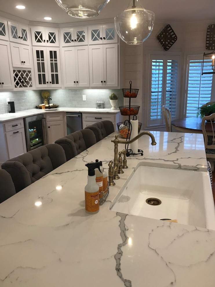 Inspiration for a mid-sized transitional u-shaped medium tone wood floor and brown floor eat-in kitchen remodel in Atlanta with a farmhouse sink, shaker cabinets, white cabinets, subway tile backsplash, stainless steel appliances, an island and granite countertops