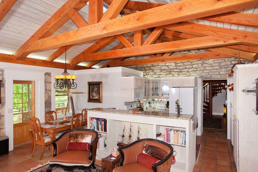 Open concept kitchen - mid-sized rustic l-shaped open concept kitchen idea in Austin with a single-bowl sink, recessed-panel cabinets, white cabinets, white appliances and an island