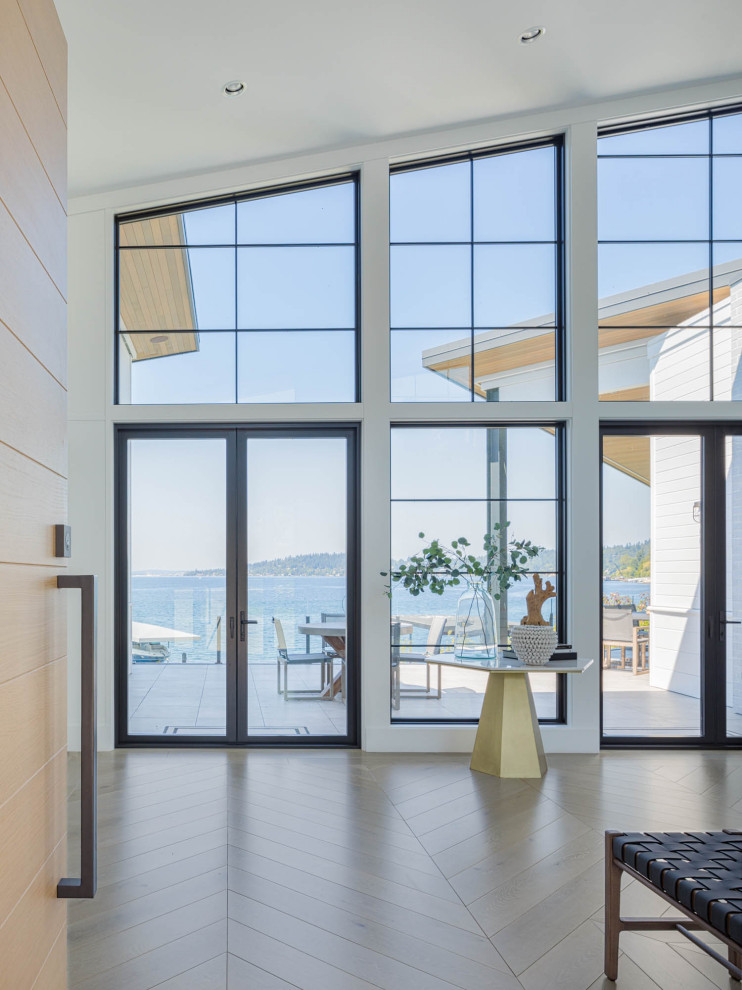 Photo of a beach style foyer in Seattle with white walls, light hardwood floors, a single front door, a light wood front door and vaulted.