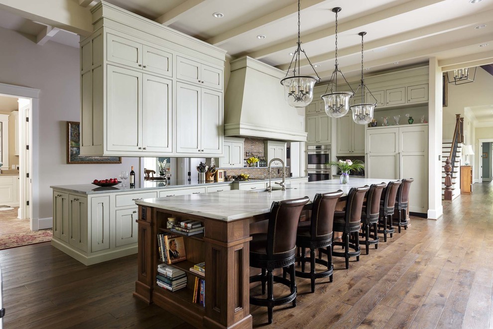 Inspiration for an expansive traditional l-shaped open plan kitchen in Nashville with a farmhouse sink, flat-panel cabinets, green cabinets, marble benchtops, brown splashback, panelled appliances, medium hardwood floors and with island.