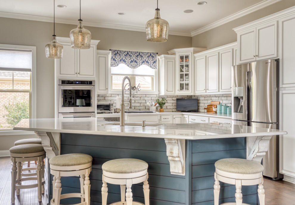Transitional u-shaped medium tone wood floor and brown floor kitchen photo in Other with an undermount sink, recessed-panel cabinets, white cabinets, quartz countertops, white backsplash, subway tile backsplash, stainless steel appliances, an island and white countertops