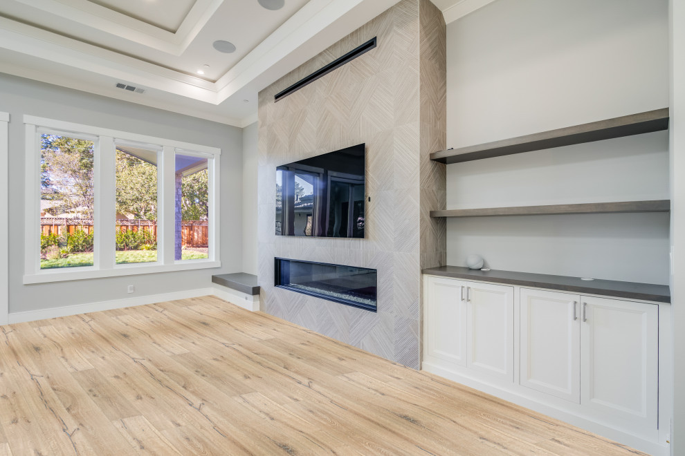 Inspiration for a large transitional formal open concept living room in San Francisco with grey walls, light hardwood floors, a standard fireplace, a tile fireplace surround, a wall-mounted tv, white floor and recessed.