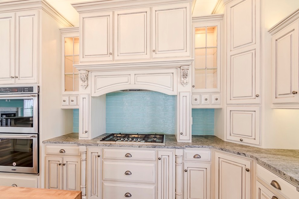 Kitchen - large transitional u-shaped dark wood floor and brown floor kitchen idea with a farmhouse sink, raised-panel cabinets, beige cabinets, blue backsplash, glass tile backsplash, paneled appliances, an island and gray countertops