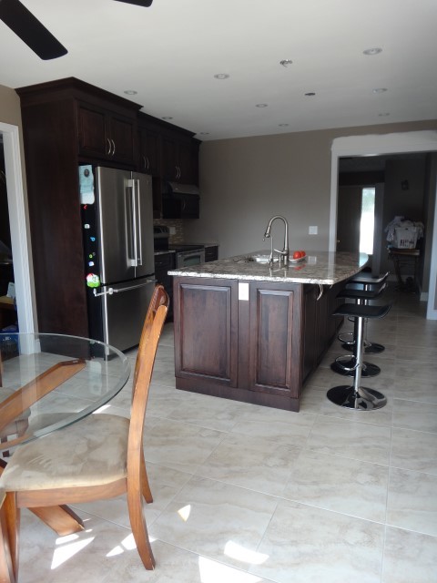 Inspiration for a large transitional galley porcelain tile eat-in kitchen remodel in Toronto with raised-panel cabinets, dark wood cabinets, granite countertops and an island