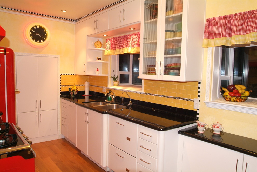 Small eclectic galley separate kitchen in San Luis Obispo with an undermount sink, flat-panel cabinets, white cabinets, granite benchtops, yellow splashback, ceramic splashback, coloured appliances, light hardwood floors and no island.