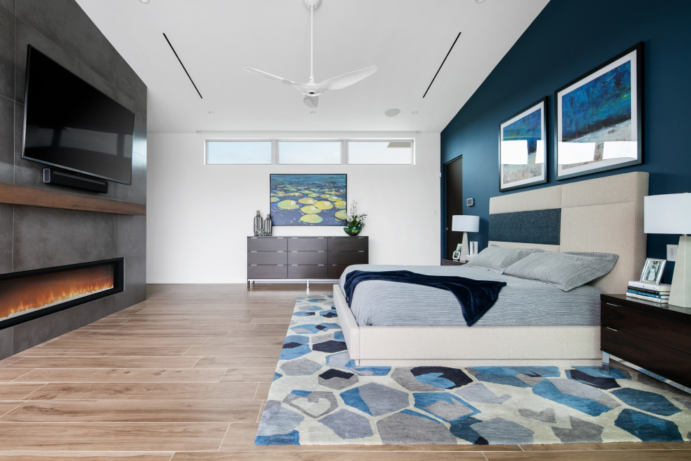 Modernes Hauptschlafzimmer mit weißer Wandfarbe, braunem Holzboden, Gaskamin, Kaminumrandung aus Beton und braunem Boden in Tampa