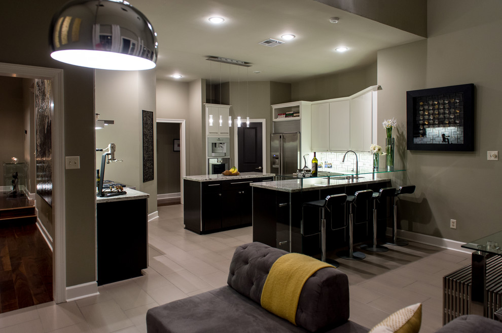 This is an example of a mid-sized contemporary u-shaped eat-in kitchen in New Orleans with an integrated sink, flat-panel cabinets, black cabinets, granite benchtops, multi-coloured splashback, stainless steel appliances, limestone floors and with island.
