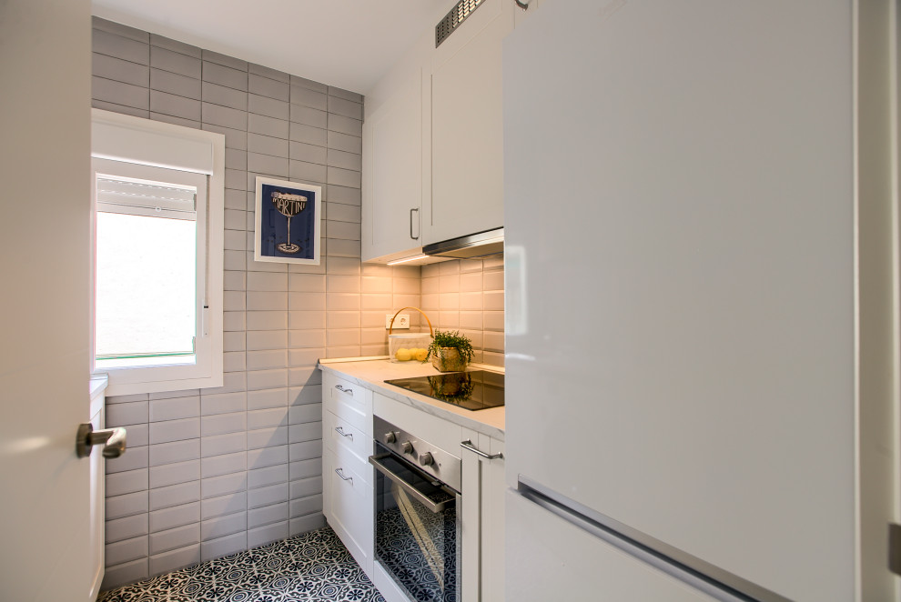 Small midcentury galley separate kitchen in Madrid with a single-bowl sink, shaker cabinets, white cabinets, laminate benchtops, grey splashback, ceramic splashback, white appliances, ceramic floors, no island, grey floor and white benchtop.