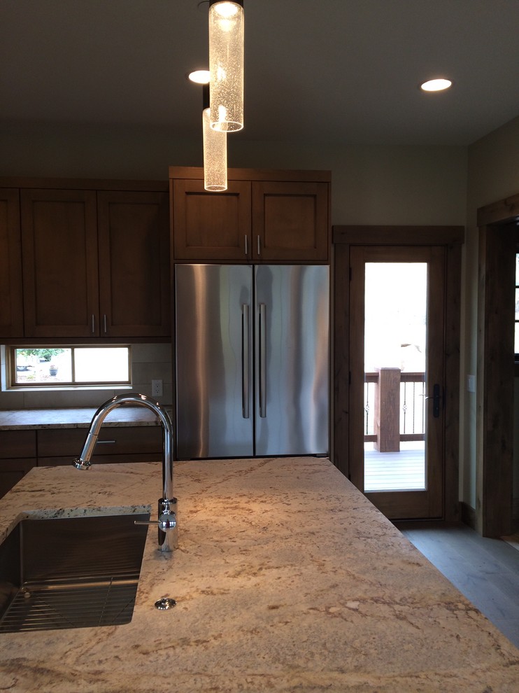 Inspiration for a small transitional l-shaped medium tone wood floor kitchen remodel with an undermount sink, shaker cabinets, medium tone wood cabinets, granite countertops, beige backsplash, porcelain backsplash, stainless steel appliances and an island