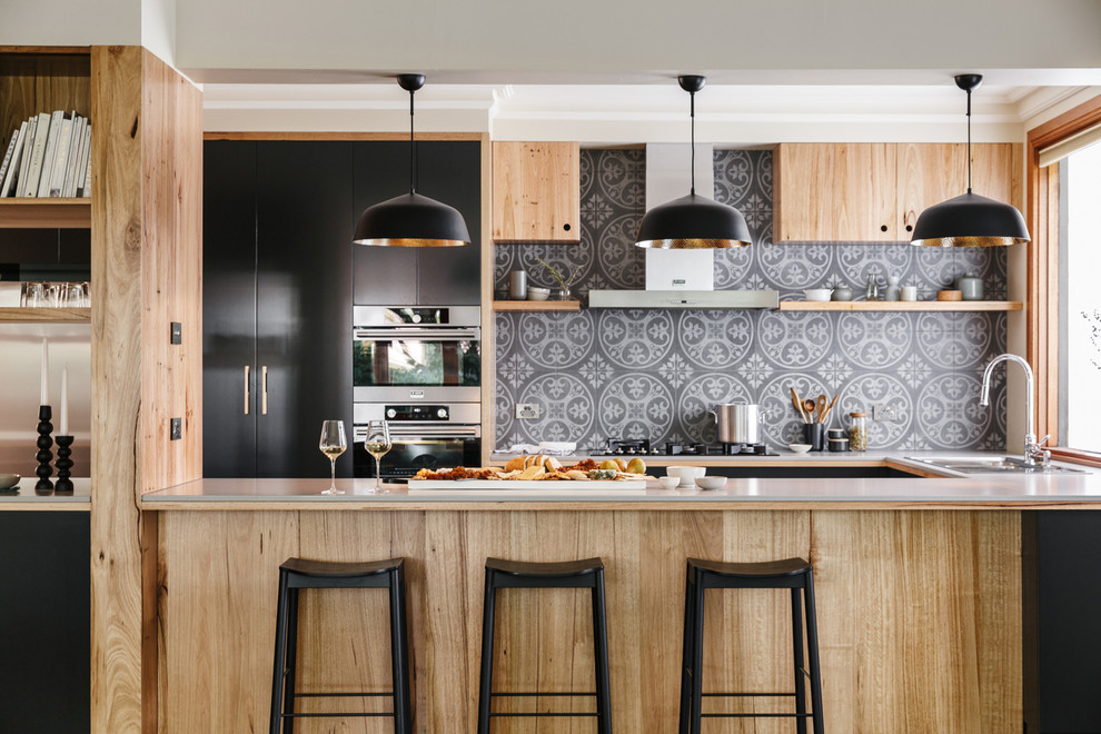 Inspiration for a large modern u-shaped open plan kitchen in Adelaide with flat-panel cabinets, medium wood cabinets, solid surface benchtops, grey splashback, ceramic splashback, stainless steel appliances, slate floors, with island and multi-coloured floor.