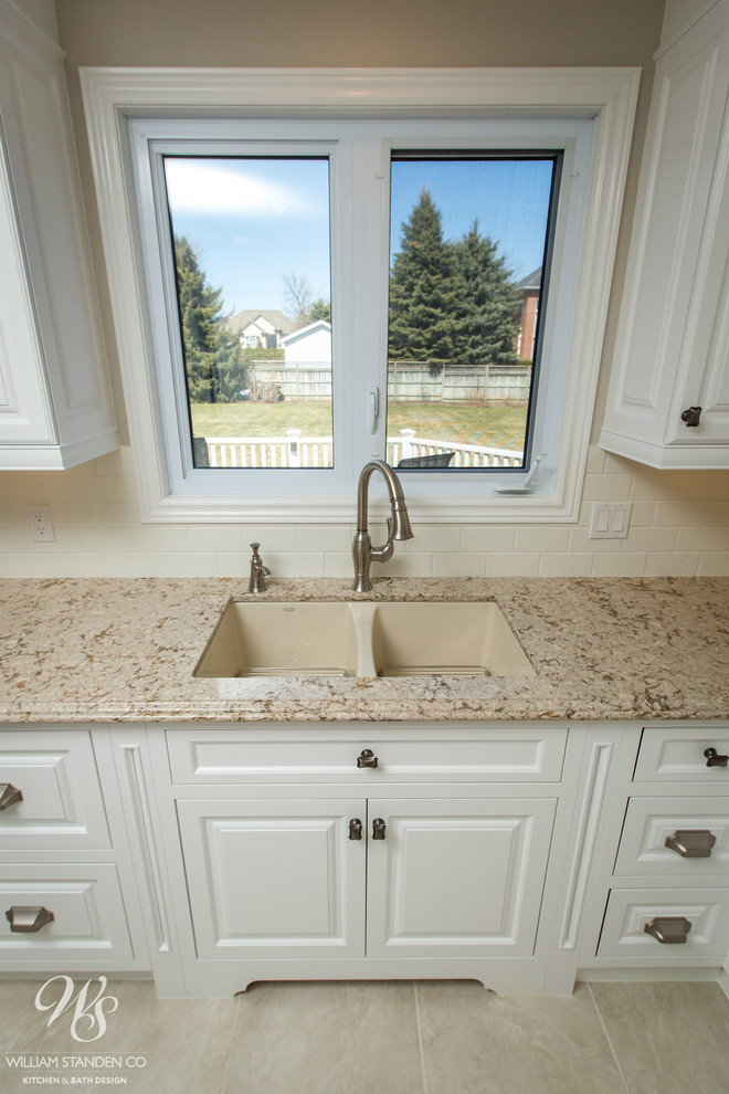 Inspiration for a mid-sized transitional u-shaped porcelain tile eat-in kitchen remodel in Toronto with an undermount sink, raised-panel cabinets, white cabinets, quartzite countertops, beige backsplash, stone slab backsplash, stainless steel appliances and an island