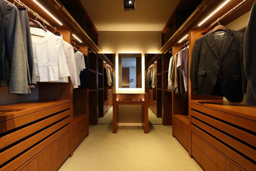 This is an example of a contemporary storage and wardrobe in Other with flat-panel cabinets, medium wood cabinets and beige floor.