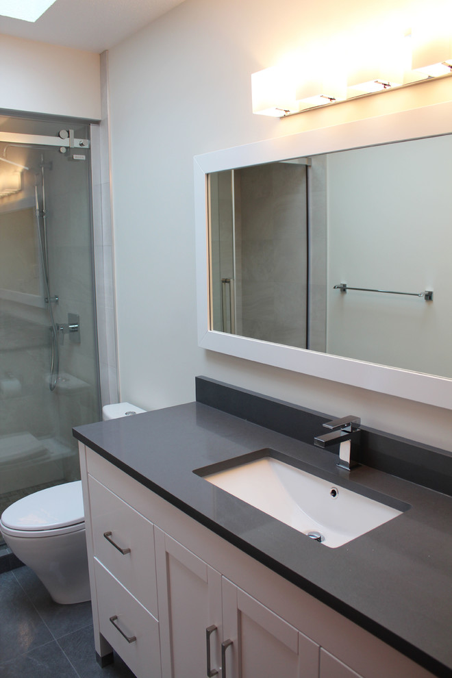 Inspiration for a mid-sized modern bathroom in Vancouver with an undermount sink, shaker cabinets, white cabinets, engineered quartz benchtops, an alcove shower, a two-piece toilet, beige tile, porcelain tile, grey walls and porcelain floors.