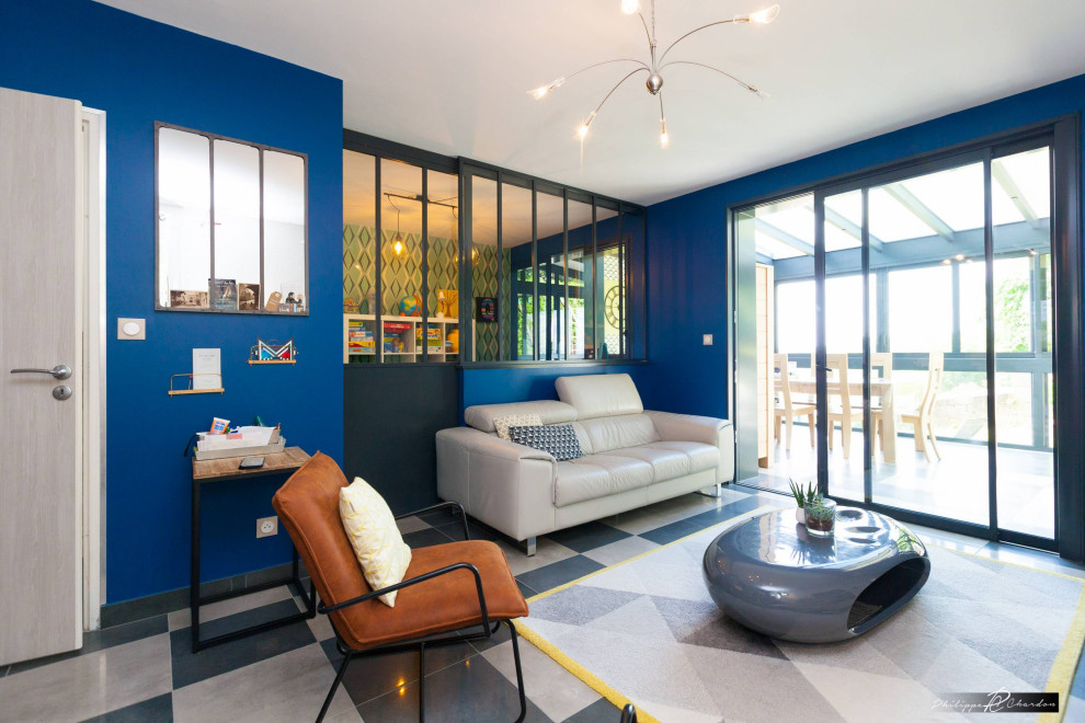 Imagen de salón abierto industrial de tamaño medio con paredes azules, suelo de baldosas de cerámica, televisor independiente y suelo negro
