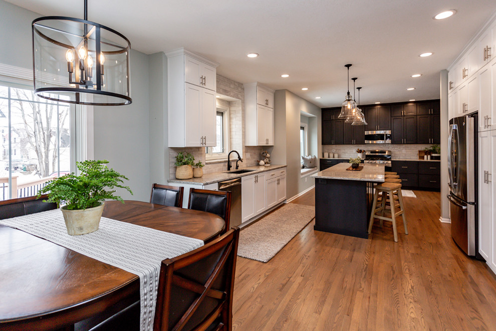 Inspiration for a large transitional u-shaped medium tone wood floor and brown floor eat-in kitchen remodel with an undermount sink, recessed-panel cabinets, white cabinets, granite countertops, white backsplash, subway tile backsplash, stainless steel appliances, an island and gray countertops