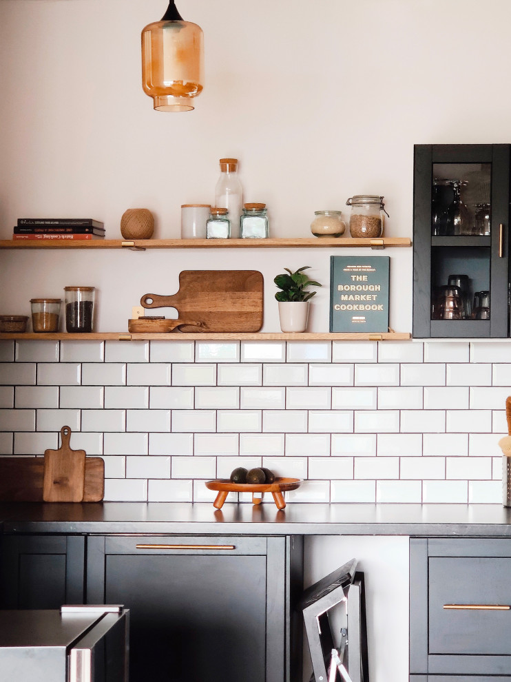Diseño de cocina vintage de tamaño medio abierta sin isla con puertas de armario negras, salpicadero blanco, salpicadero de azulejos tipo metro y encimeras negras