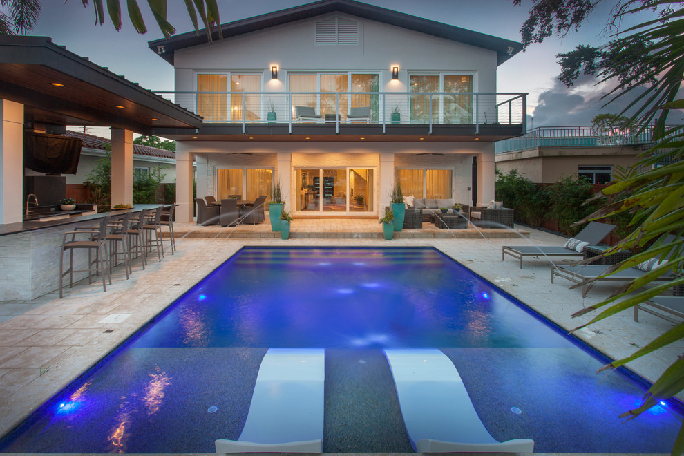 Inspiration for a large modern backyard rectangular lap pool in Tampa with natural stone pavers.