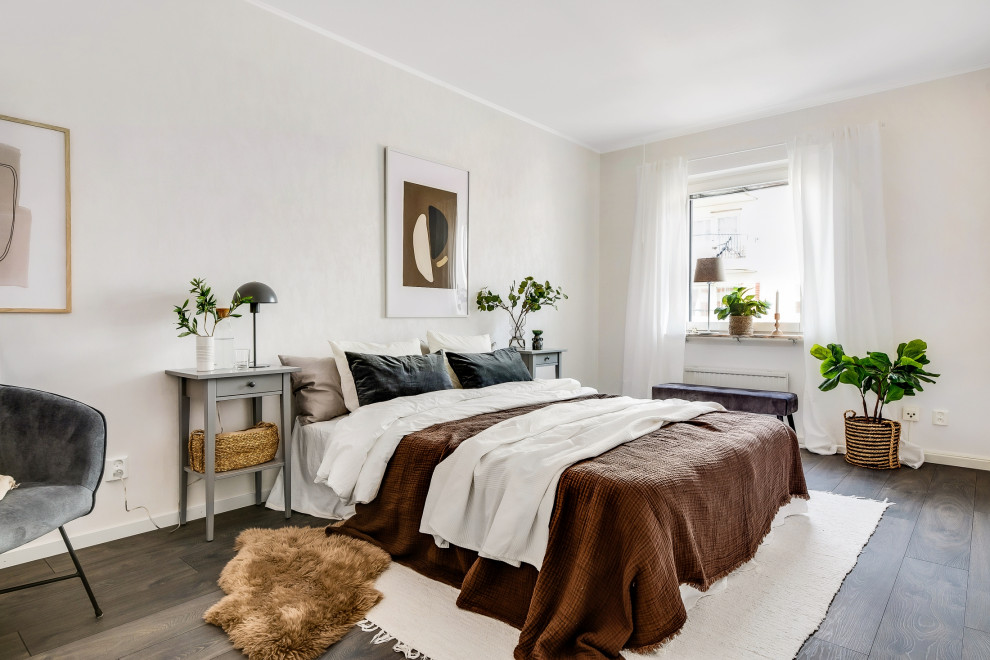 Large scandinavian bedroom in Stockholm with beige walls, dark hardwood floors and brown floor.
