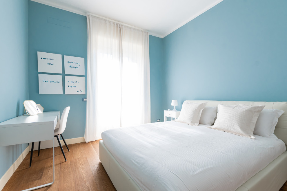 Photo of a medium sized modern master bedroom in Milan with blue walls and brown floors.