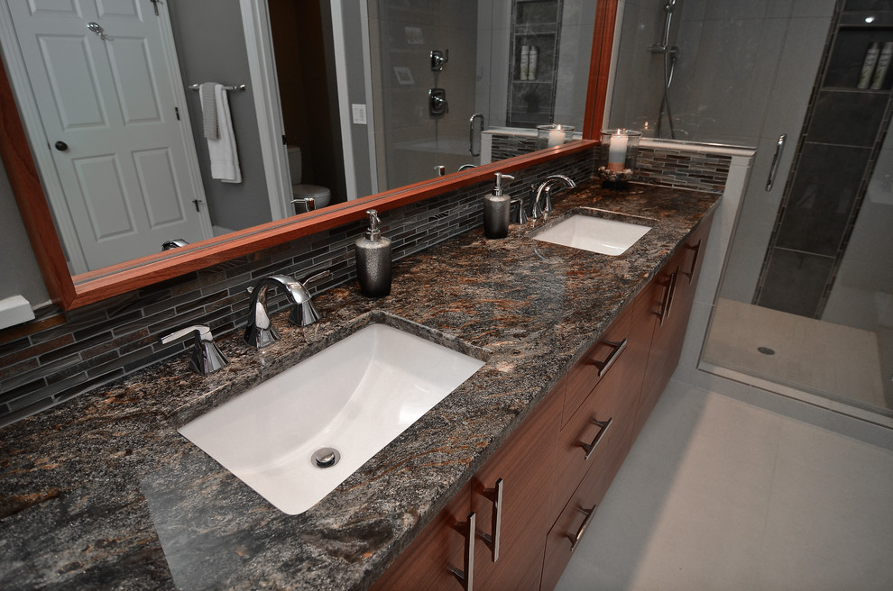 Design ideas for a mid-sized contemporary master bathroom in Portland with an undermount sink, flat-panel cabinets, medium wood cabinets, granite benchtops, an undermount tub, an alcove shower, gray tile, porcelain tile, grey walls and porcelain floors.