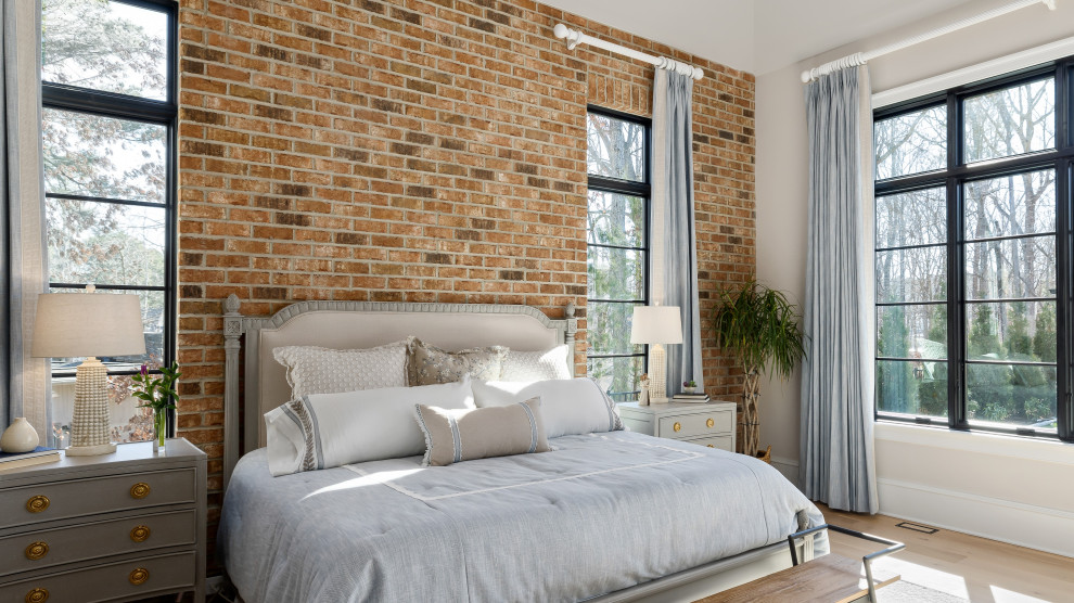 This is an example of a large transitional master bedroom in Raleigh with beige walls, light hardwood floors, no fireplace, beige floor, vaulted and brick walls.