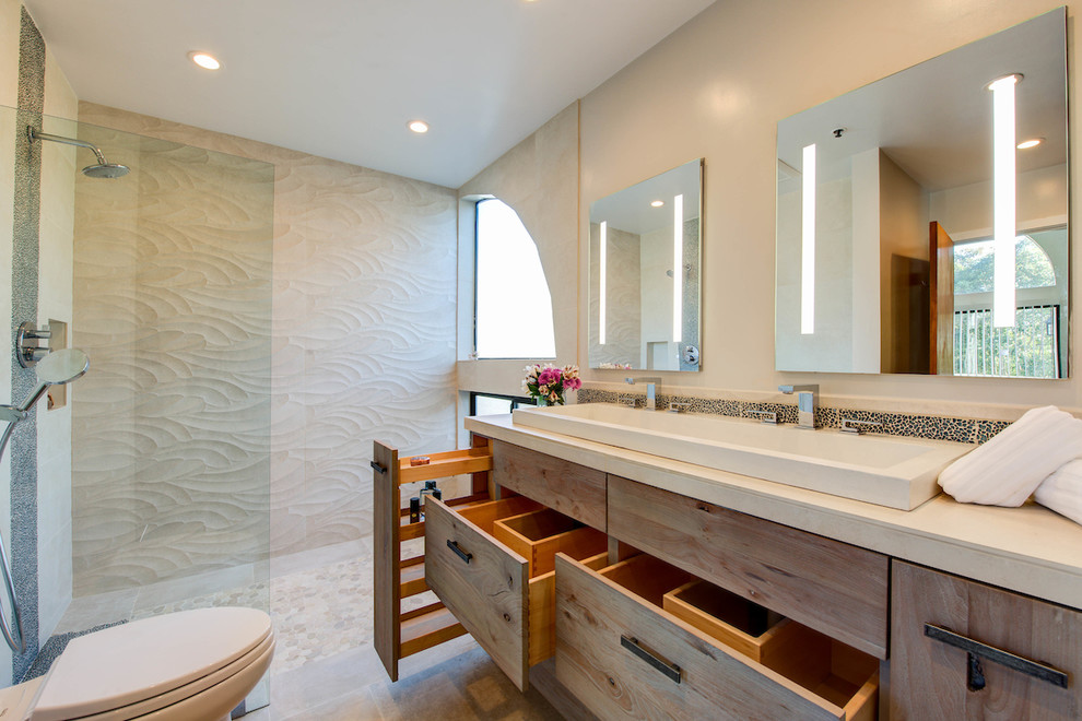Mid-sized beach style master bathroom in San Francisco with flat-panel cabinets, distressed cabinets, a curbless shower, a one-piece toilet, beige tile, porcelain tile, beige walls, porcelain floors, a trough sink and tile benchtops.
