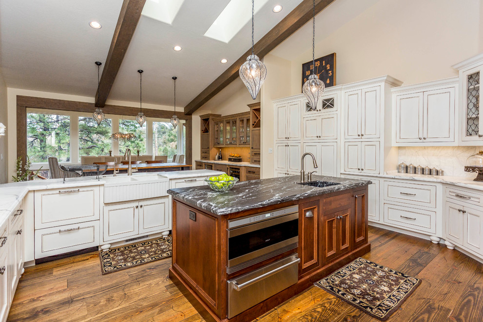 Eat-in kitchen - huge transitional u-shaped medium tone wood floor eat-in kitchen idea in Phoenix with a farmhouse sink, recessed-panel cabinets, white cabinets, marble countertops, white backsplash, paneled appliances and two islands