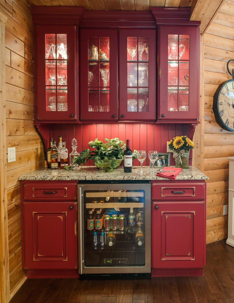 This is an example of a large traditional l-shaped home bar in Other with medium hardwood floors, raised-panel cabinets, red cabinets and red splashback.