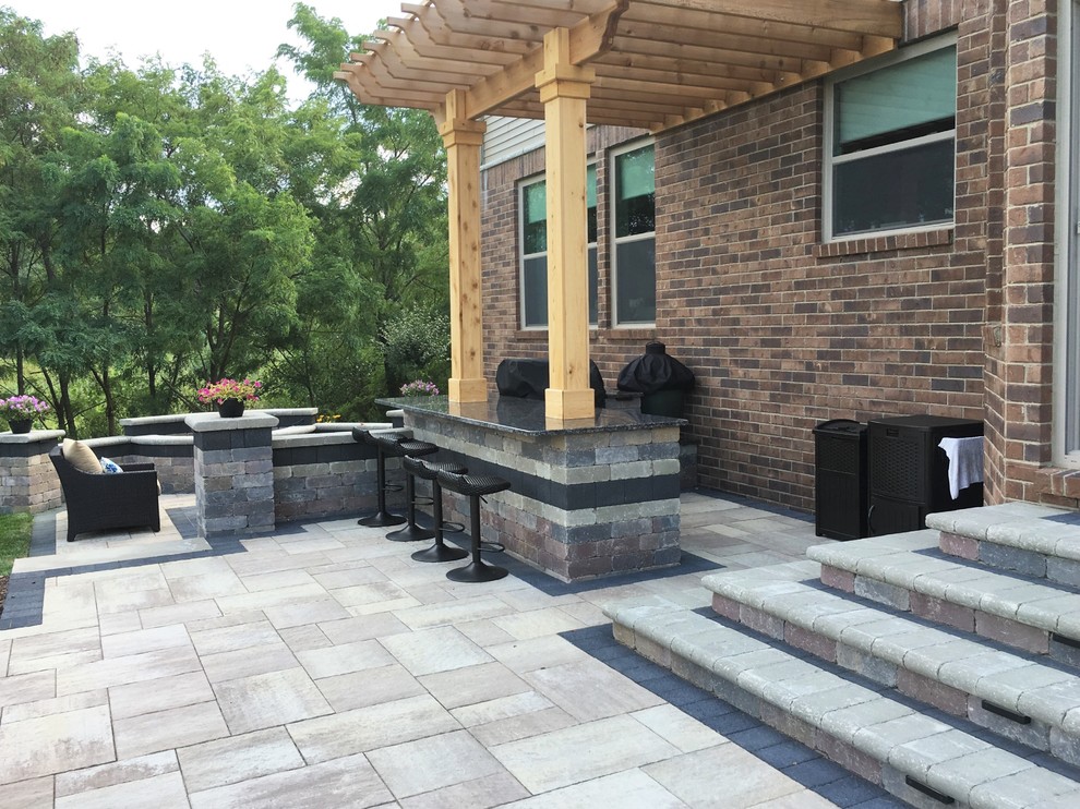 This is an example of a mid-sized contemporary backyard patio in Detroit with an outdoor kitchen, brick pavers and a pergola.