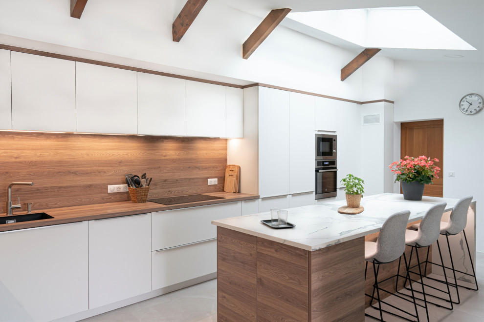 Large scandinavian l-shaped separate kitchen in Other with an undermount sink, flat-panel cabinets, white cabinets, marble benchtops, brown splashback, timber splashback, panelled appliances, concrete floors, with island, grey floor, white benchtop and exposed beam.