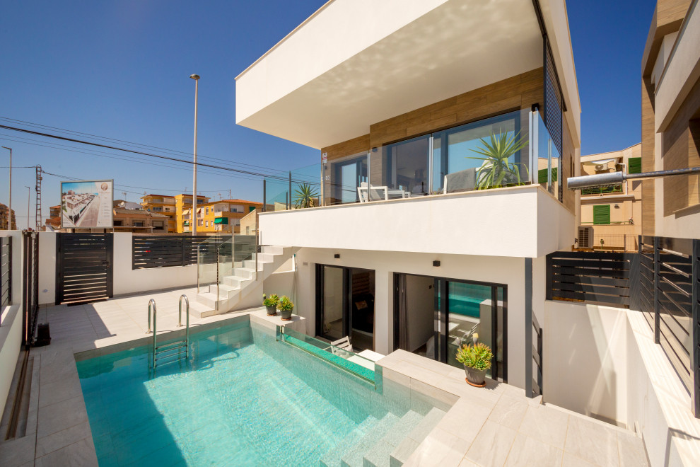 Modelo de casa de la piscina y piscina alargada minimalista grande rectangular en patio delantero con suelo de baldosas